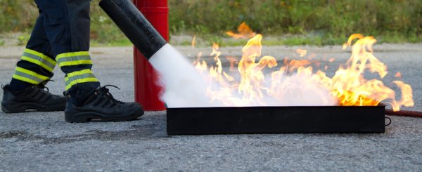 Fire extinguisher being used on a controlled fire in a metal box
