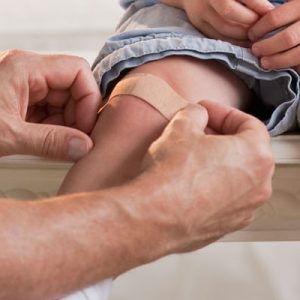 Person apply a plaster on a child's knee